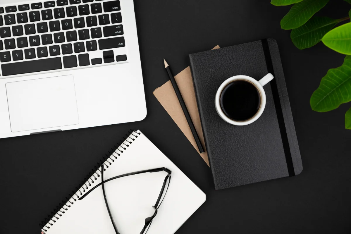 Bureau sombre avec ordinateur portable, carnets et café